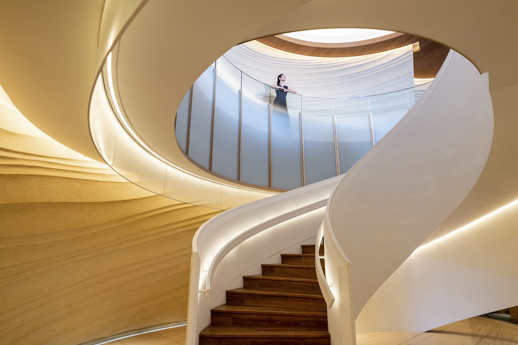 A solo traveler stands above the sweeping spiral staircase at InterContinental Yokohama Pier 8 in Japan.
