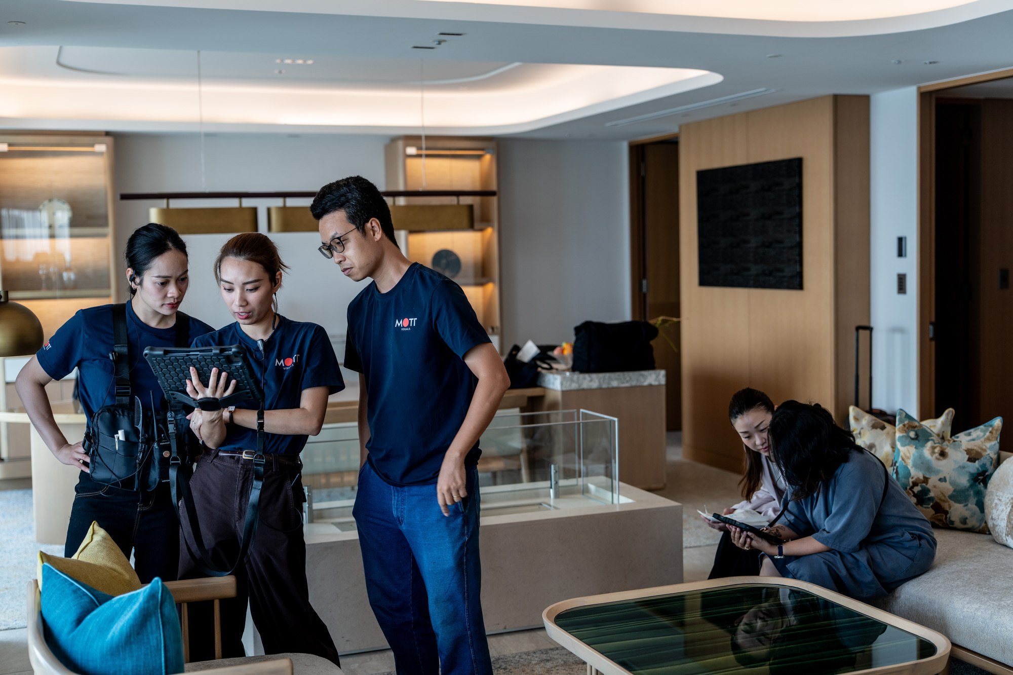The Mott Visuals production team reviews a tablet while preparing a scene inside a hotel room in Yokohama.