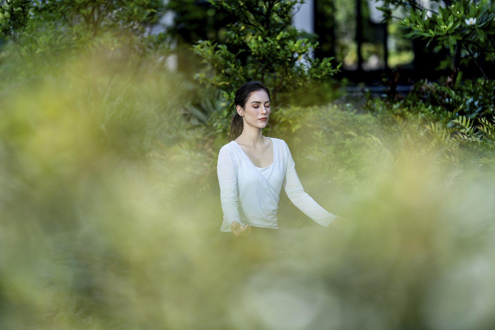 A woman in a white blouse sits among greenery in the hotel garden in Yokohama.