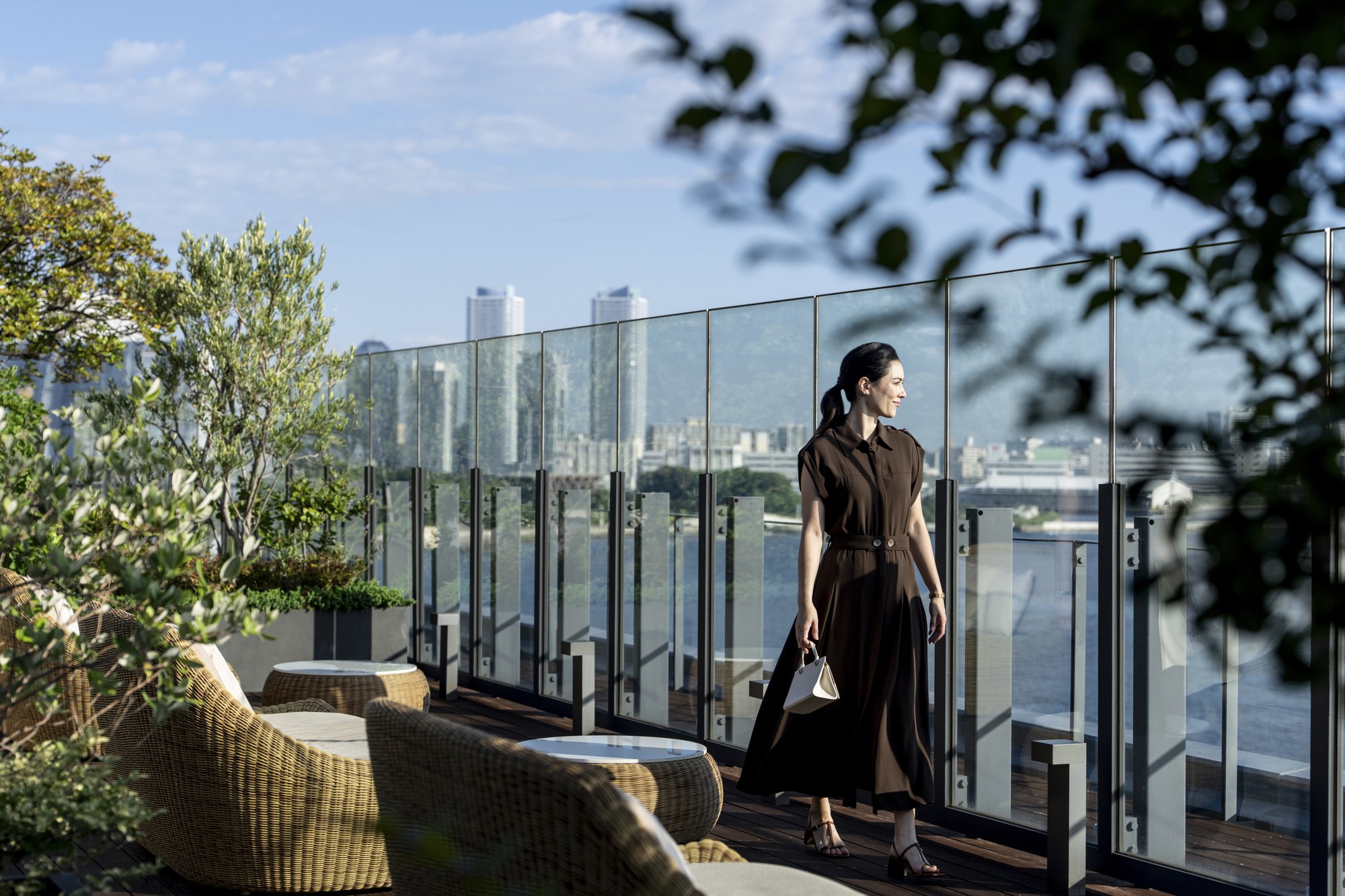A solo traveler walks beside terrace seating overlooking Yokohama at InterContinental Yokohama Pier 8.